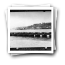 Vista geral de porto: ponte e embarcações no cais (reprodução de prova)
