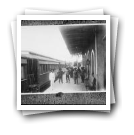 Pessoas junto a comboio parado em Estação de Caminho-de-Ferro (reprodução de prova)