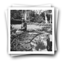 Maria Luísa Garcia, com ramos de flores, sentada numa fonte dos jardins do Palácio Nacional de Queluz